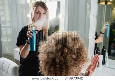 Closeup Of Hairdresser Using Hairspray On Clients Hair At Salon