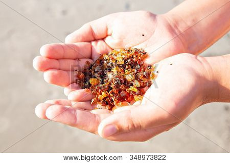 Solar Amber Stones In The Arms Of A Child S Hands On The Sea On A Background Of Sand. View From Abov