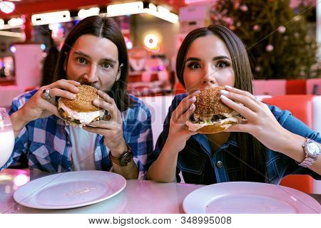 Modern Lovely Couple Enjoys Their Amazing Tasty Meal, Burger With Meat Patty, Sauce, Vegetables And 