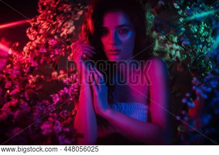 A Fantastic Shot Of A Girl In Flowers With Neon Multicolored Light And Phantasmagoria. The Concept O