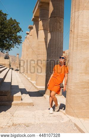A Woman Stands In The Ancient Acropolis Of Lindos Against The Background Of The Colonade, Greece, Rh