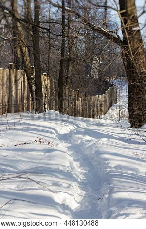 A Trodden Footpath Through The Snow In Winter Along A Wooden Fence