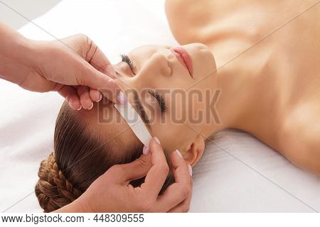 Beautician Is Removing Hair From Beautiful Female Face With Hot Wax. Woman Has A Beauty Treament Pro