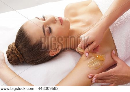 Beautician Is Removing Hair From Young Female Armpits With Hot Wax. Woman Has A Beauty Treament Proc