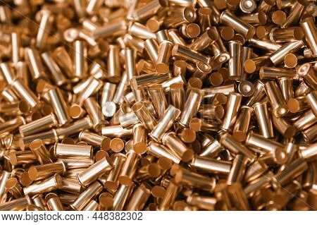 Large Pile Of New Golden Shells Of Bullets As Background At Bright Light In Production Plant Worksho
