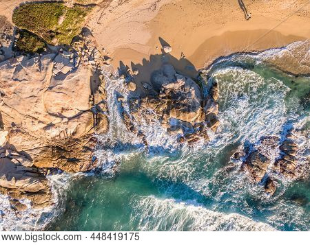 Aerial View Of Two People Walking Past Rocks Along A Sandy Beach At Aregno Plage Near Algajola In Th