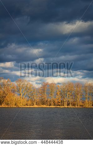 Dramatic Sunset Sky Above Pond With Leafless Tree Aley On Water Edge. Czech Landscape