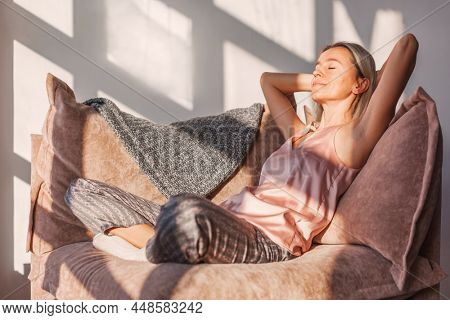 Adult girl relaxing at home on couch, enjoying free time. Middle-aged woman rela[x on sofa at home