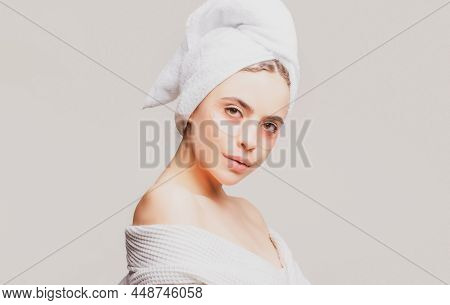 Young Beautiful Girl With A Towel On Head And A White Robe Girl Cares For The Skin Using Patches Und