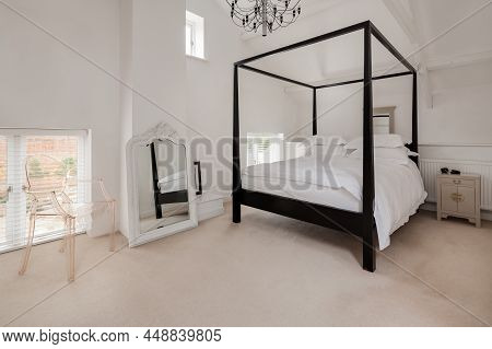 Luxury Modern Furnished Chic Bedroom In White With Dark Wood Four Poster Bed And Prominent Mirror Wi