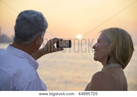 Senior Man And Woman Using Mobile Phone To Take Photo