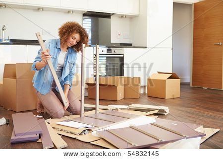 Woman Putting Together Self Assembly Furniture In New Home