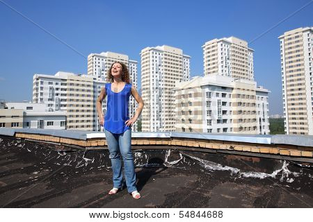 Happy woman with raised up his head stands on roof of the building