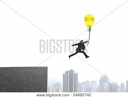 Businessman Jumping From Bulding Top To Catch Glowing Lamp Balloon