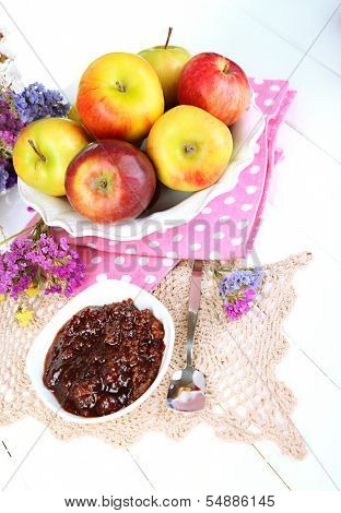 Juicy apples on plate on white wooden table