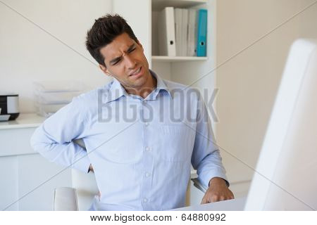 Casual businessman touching his sore back in his office