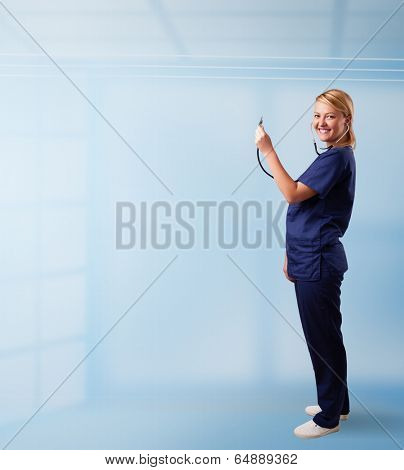 Pretty young nurse in hospital listening to empty copy space with sthetoscope