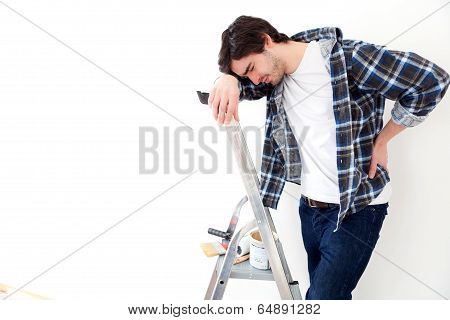 Young Man Suffering While Working On A Stepladder