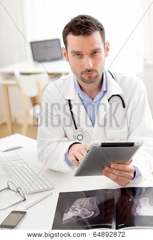 Portrait Of A Young Doctor Using Tablet At Work