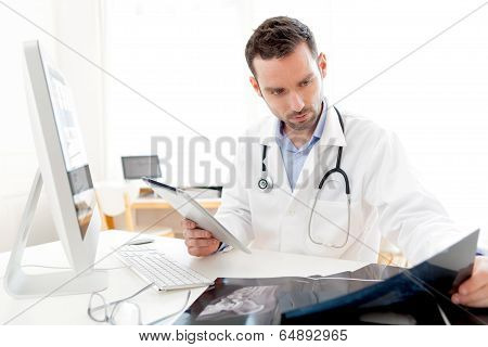 Portrait Of A Young Doctor Using Tablet At Work