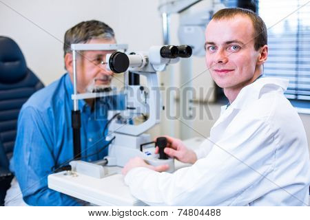 Optometry concept - senior man having his eyes examined by an eye doctor (color toned image; shallow DOF)