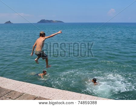Boys jumping into sea off of the jetty on Petra seafront
