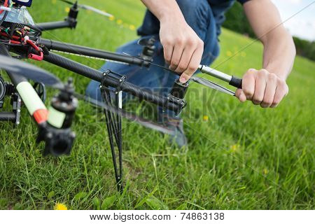 Closeup of young engineer tightening propeller of UAV drone with hand tool in park