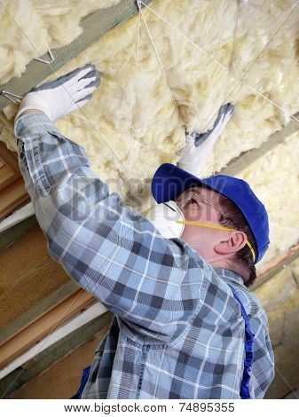 Worker thermally insulating a house attic using mineral wool