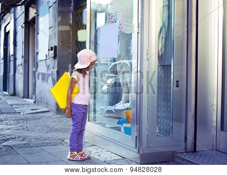 cute little girl with shopping bags walking in the city