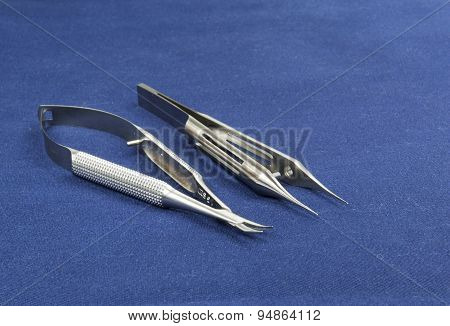 Two Microsurgical Instruments On Blue Background