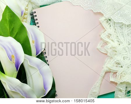 empty note book opening with lace decor and artificial calla flowerbackground