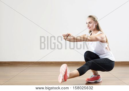 Young fit woman works out in the fitness class. Squats on one leg. Space for placing text.
