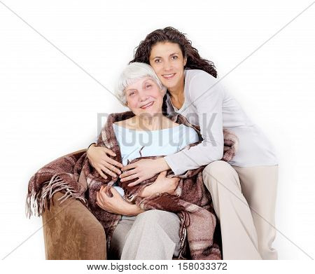 elderly woman and her daughter sitting in a chair with a blanket hug mother grandmother. on a white background