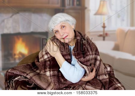 Happy beautiful elderly woman sits covered with a blanket in the room. mother. grandmother
