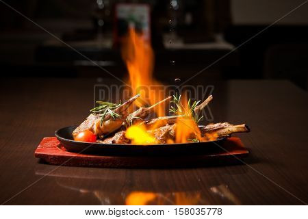 Juicy roasted Prime rib with herbs under fire on a wooden table