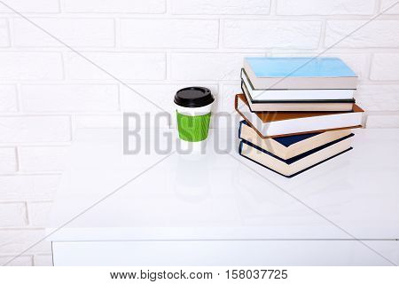 Workspace near brick wall. Cup of coffee and many books. Copy space