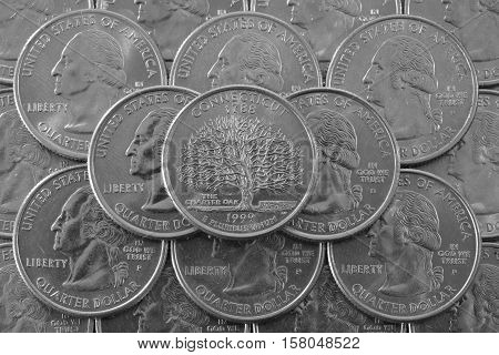 Coins of USA. Pile of the US quarter coins with George Washington and on the top a quarter of Connecticut State.