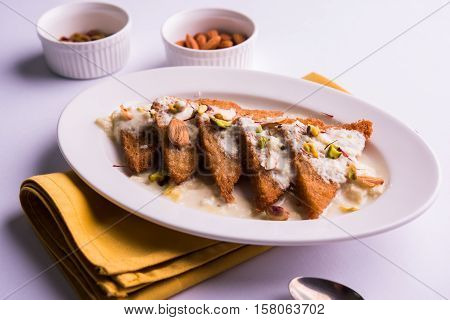 Shahi Tukda prepared - deep fried bread in ghee, garnish with sweetened cream and dry fruits.