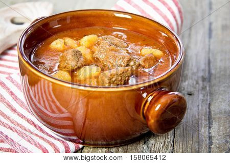 goulash in brown bowl on wooden table