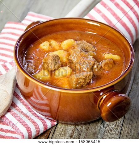 goulash in brown bowl on wooden table