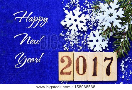 Happy New Year 2017 greeting card. Happy New Year decoration with snowflakes and fir tree branch on blue background.Selective focus.