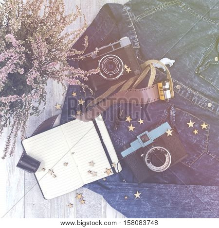 Old vintage camera, white blank diary, jeans shirt and wooden stars laying on the wooden desk. Top view