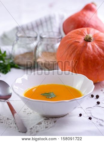 Autumn pumpkin orange soup on white tablecloth.