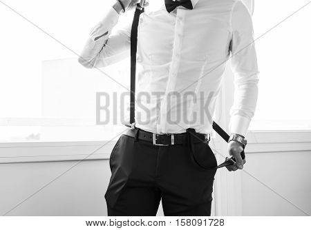 Groom pulling on the suspenders. Final wedding preaprations.