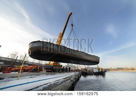 MOSCOW, RUSSIA - NOVEMBER 11, 2016: State Unitary Enterprise Mosvodostok performs recovery vessels on coastal winter parking. Car crane lifts the barge.