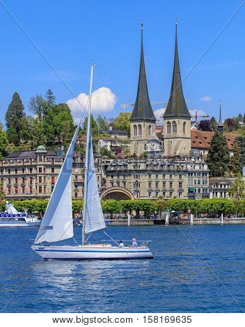 Lucerne, Switzerland - 8 May, 2016: view on Lake Lucerne from the Bahnhofquai quay - people in a sailboat, towers of the Church of St. Leodegar in the background. Lake Lucerne is a lake in central Switzerland, the fourth largest in the country.