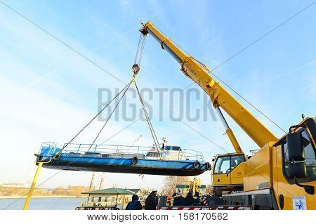 MOSCOW, RUSSIA - NOVEMBER 11, 2016: State Unitary Enterprise Mosvodostok performs recovery vessels on coastal winter parking. The ship rises transferred to shore with the help of truck crane.