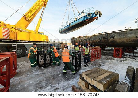 MOSCOW, RUSSIA - NOVEMBER 11, 2016: State Unitary Enterprise Mosvodostok performs recovery vessels on coastal winter parking. The workers make a place in the ship installation.