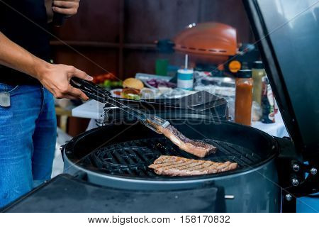 Raw meat is being prepared on grill. Beef steak being cooked