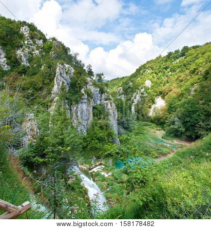A river meandering between stone hills of the canyon. Sunny day white fluffy clouds in the sky. Plitvice lakes national park Croatia